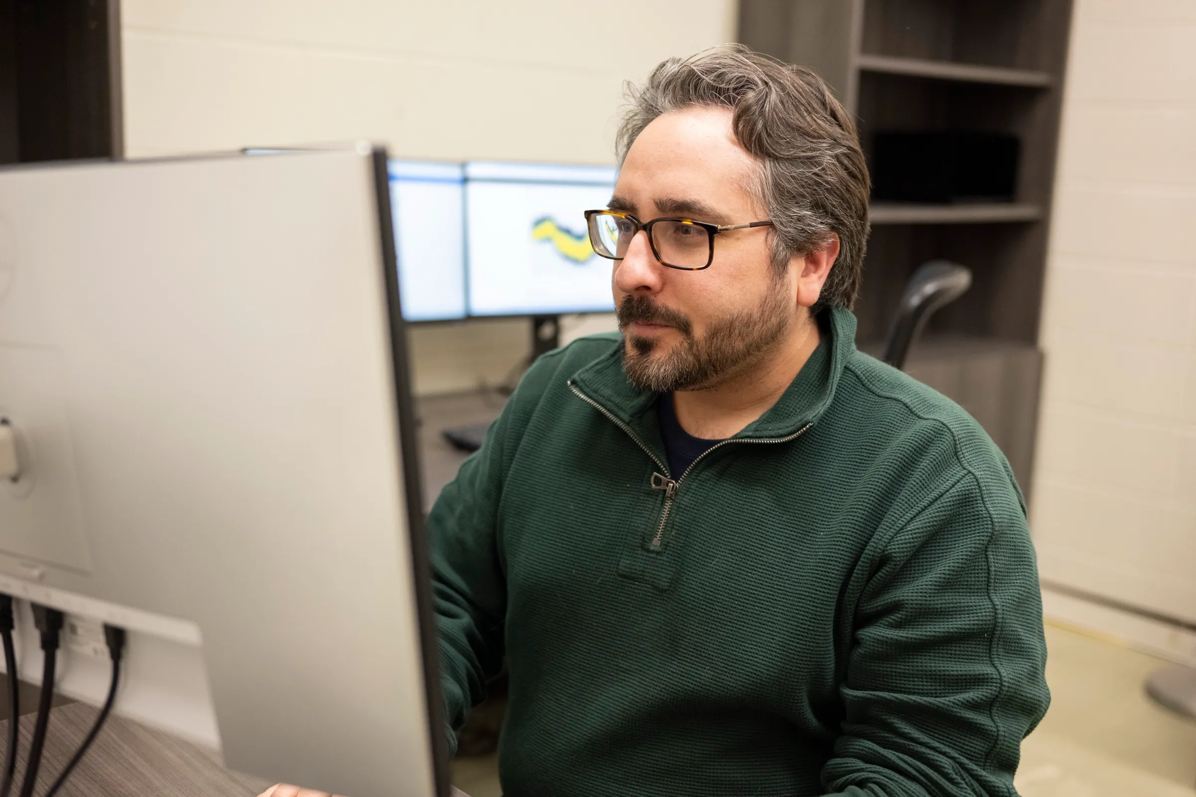 Jeff Girard at a workstation, looking at a monitor showing a data plot.
